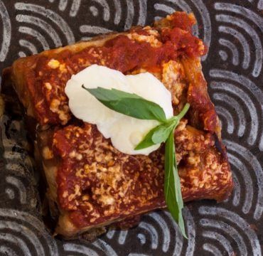 Primo piano di un pezzo di pizza con salsa e formaggio su un piatto.