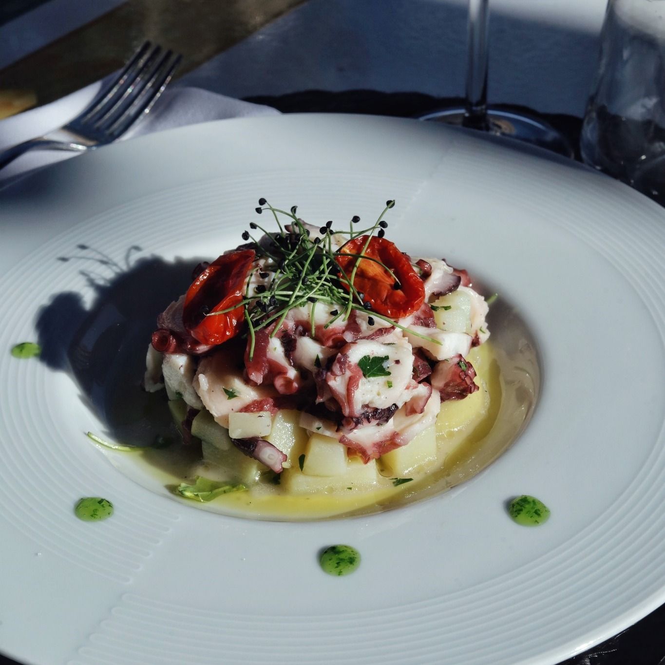 Un piatto bianco con sopra un'insalata di polpo e patate