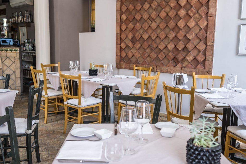 Un ristorante pieno di tavoli e sedie con sopra piatti e bicchieri.