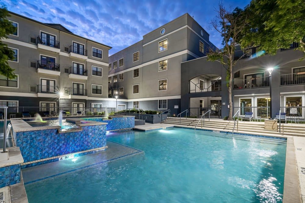 A large swimming pool in front of a building at night at Marquis at Texas Street in Dallas, TX.