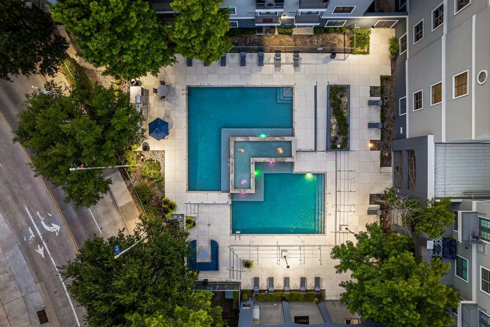 An aerial view of a large swimming pool surrounded by trees at Marquis at Texas Street in Dallas, TX.