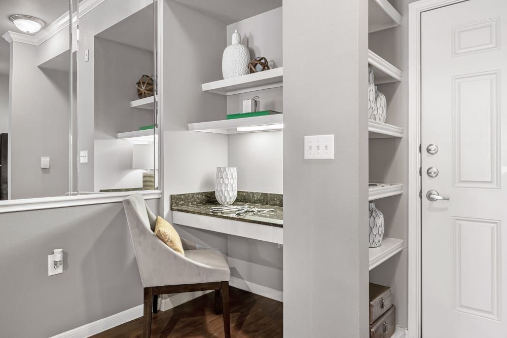 Home office space with a desk, chair, shelves, and a mirror at Marquis at Texas Street in Dallas, TX.