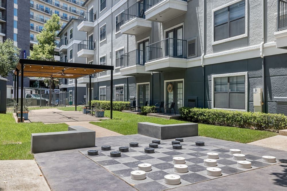 A large outdoor checkers board is sitting on the ground at Marquis at Texas Street in Dallas, TX.