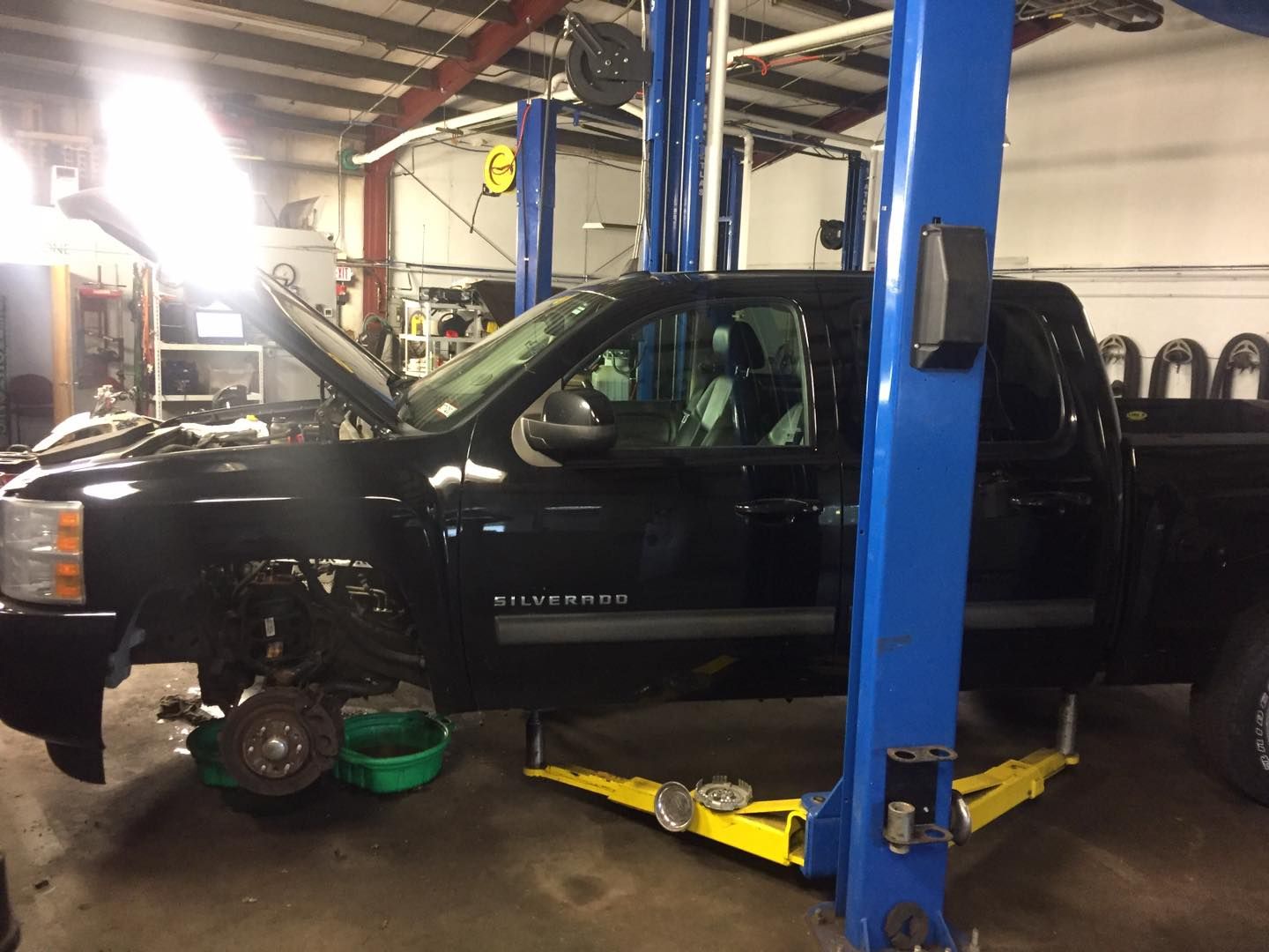A black truck is sitting on a lift in a garage.