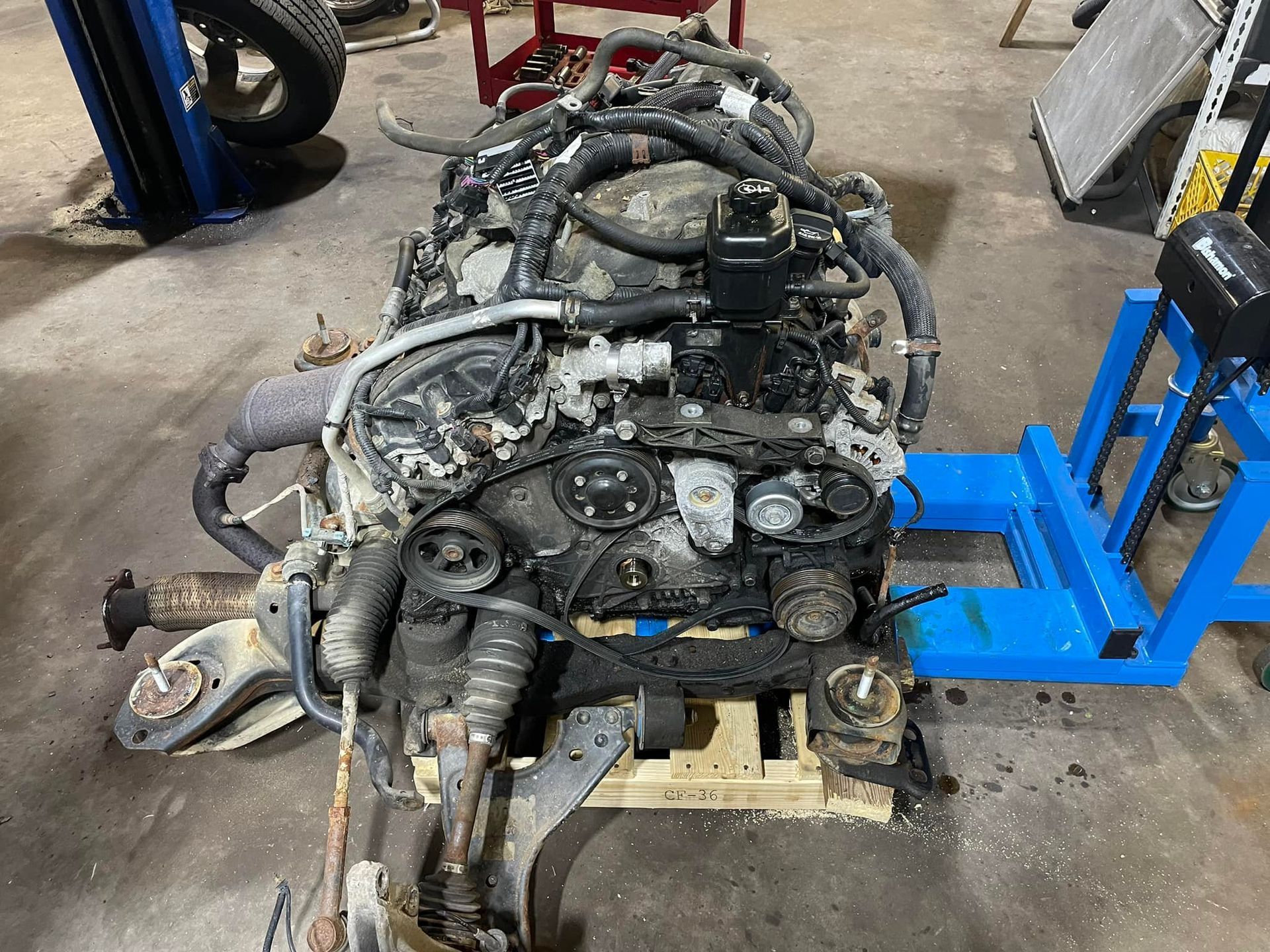 A large engine is sitting on top of a wooden table in a garage.