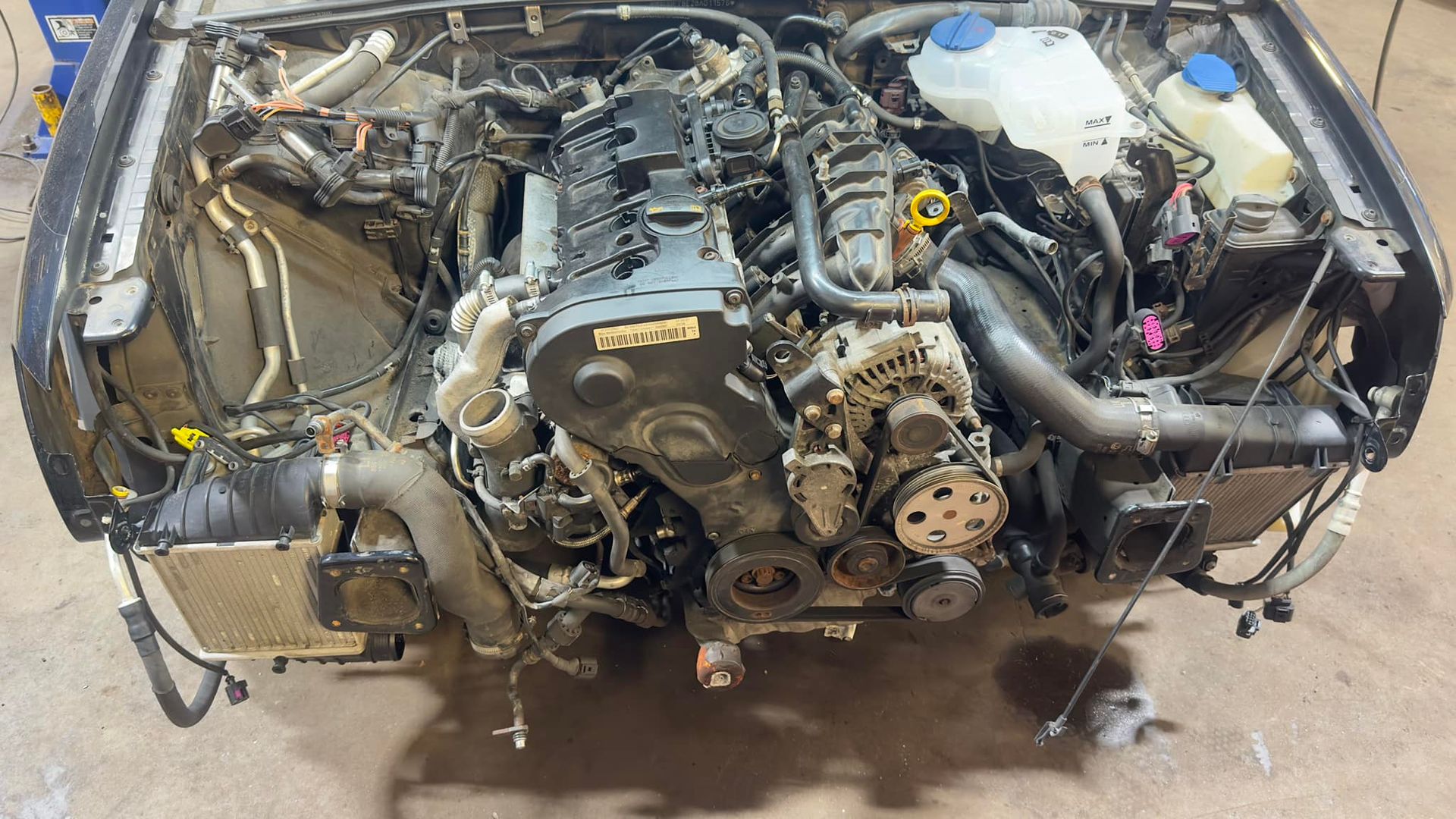 A car engine is being removed from a car in a garage.