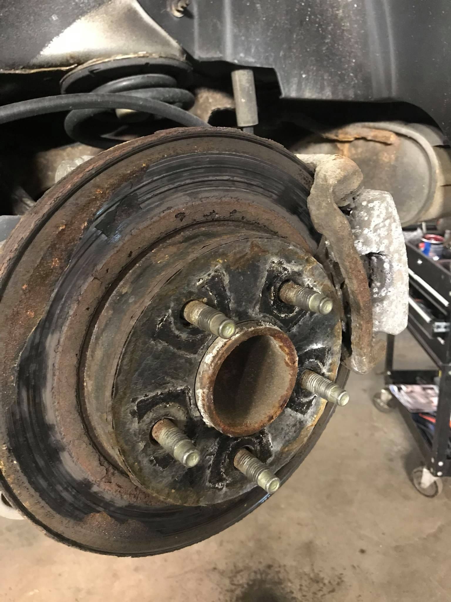 A close up of a rusty brake disc on a car.