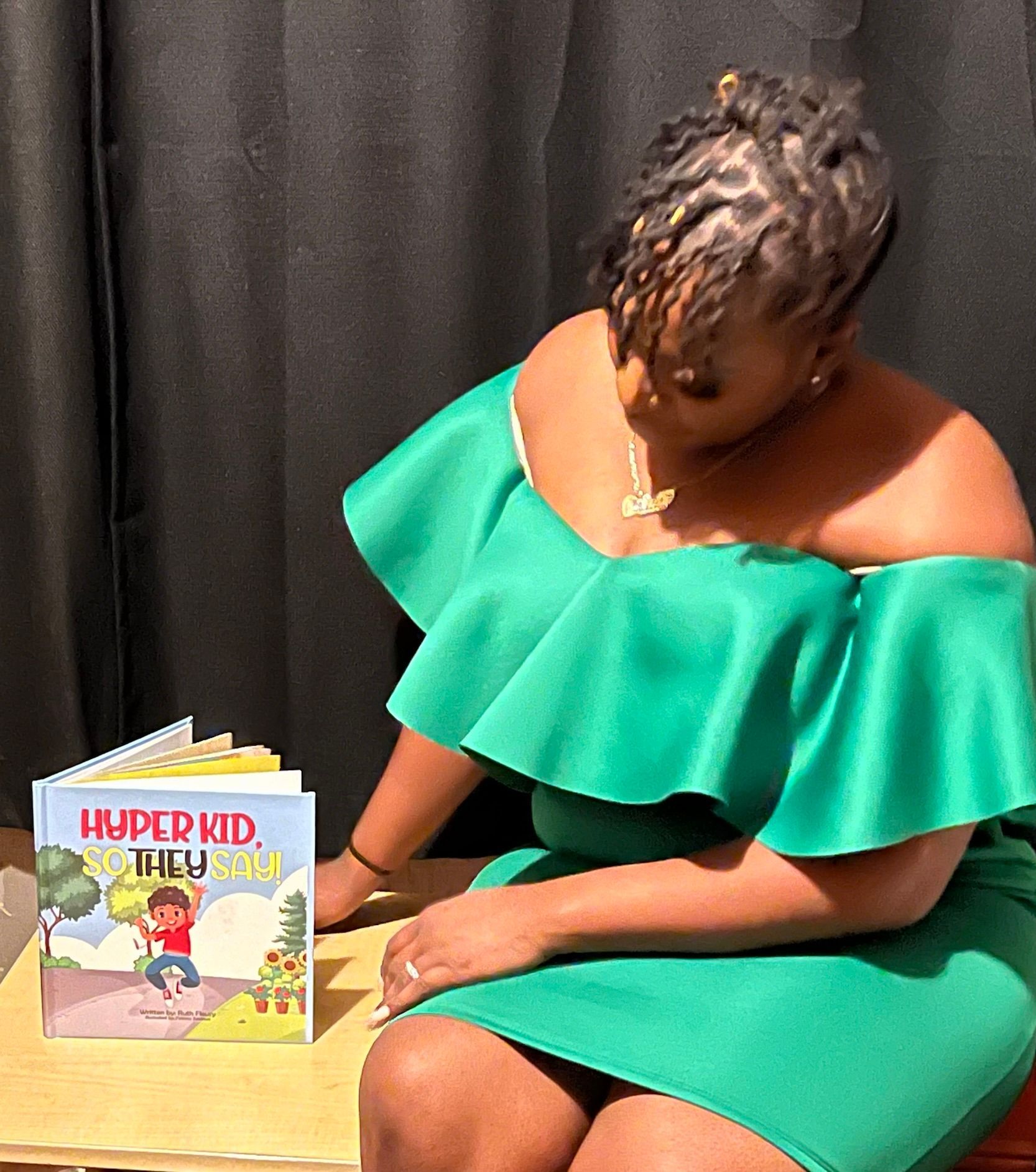 Woman in green dress holds a book titled 