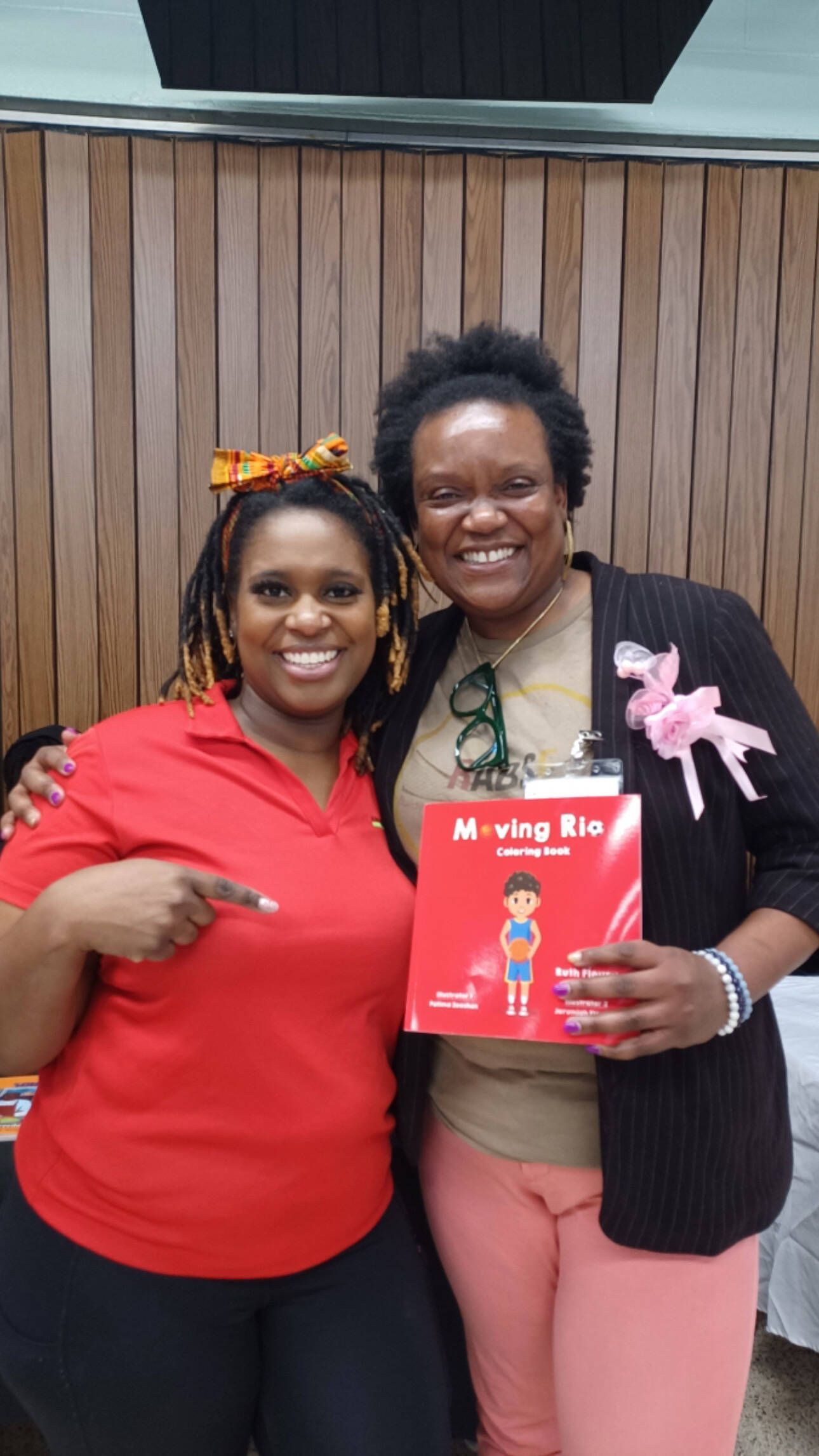 Two women smiling, holding a book titled 