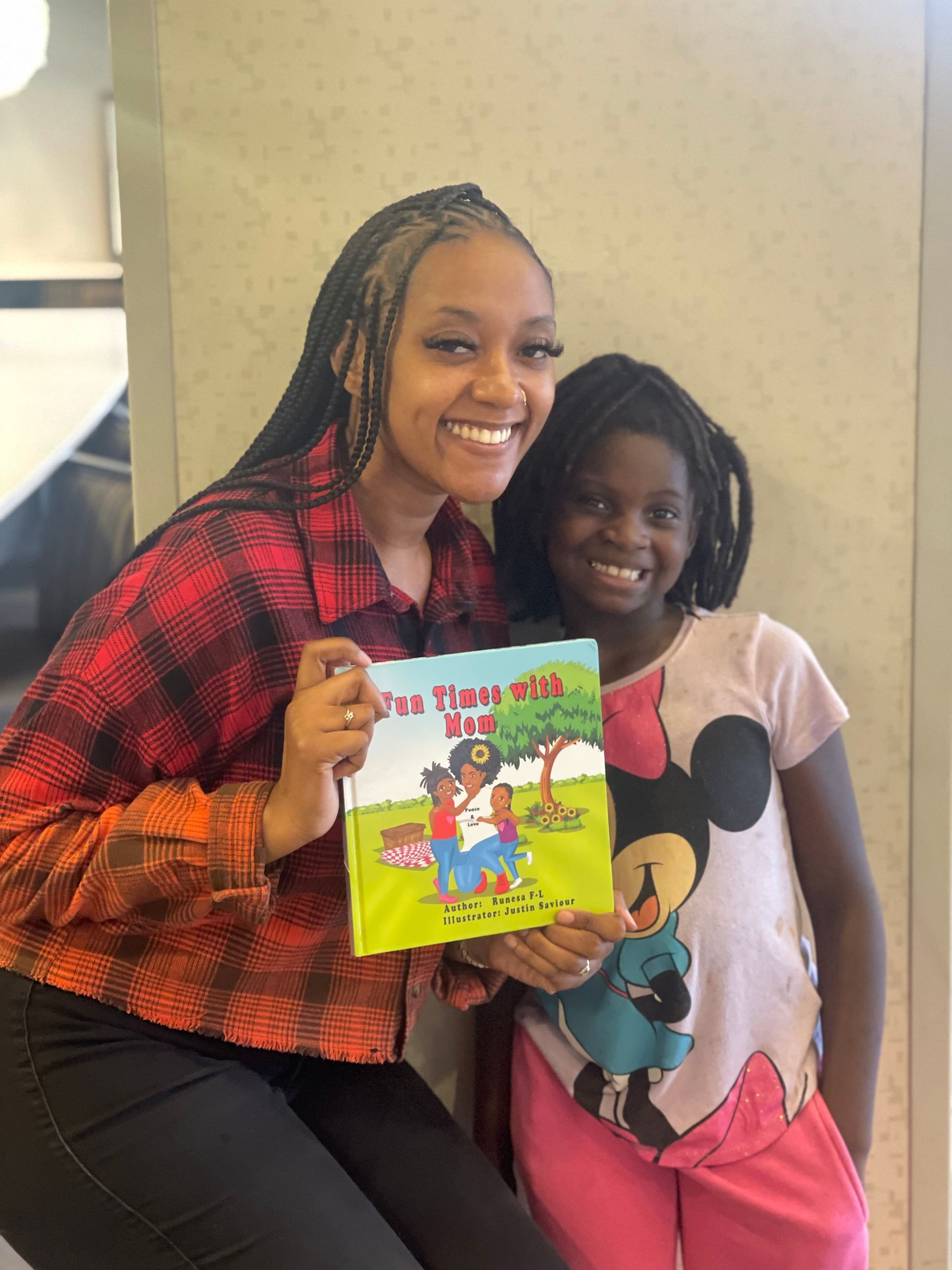 Woman and child smiling, holding a book titled 