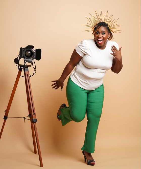 A woman in green pants is running in front of a camera on a tripod