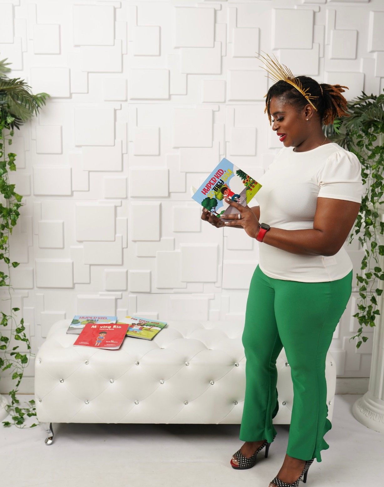 A woman in green pants and a white shirt is reading a book.