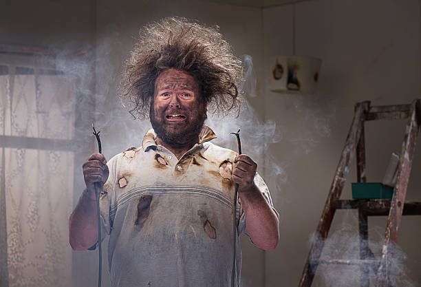 A man with a beard is holding two wires in his hands.
