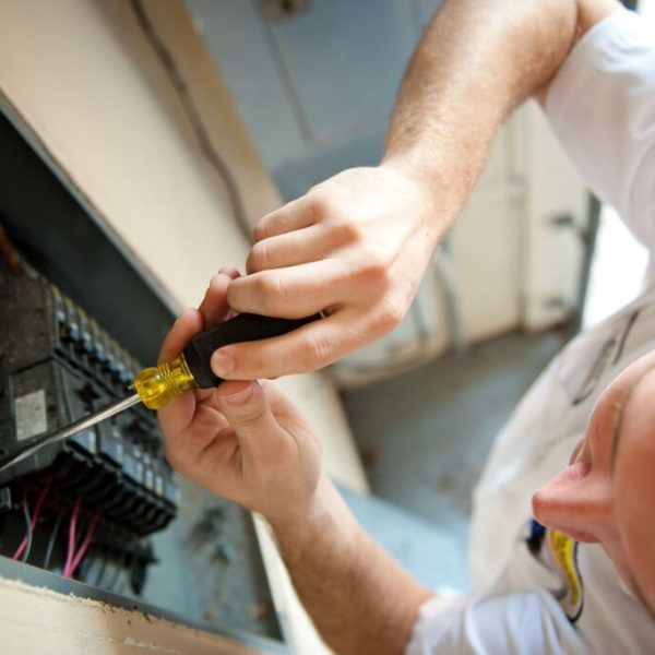 Man in Mister Sparky shirt inspects electrical panel