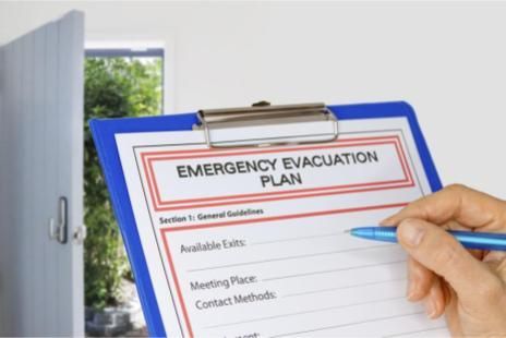 A person is writing on an emergency evacuation plan on a clipboard.