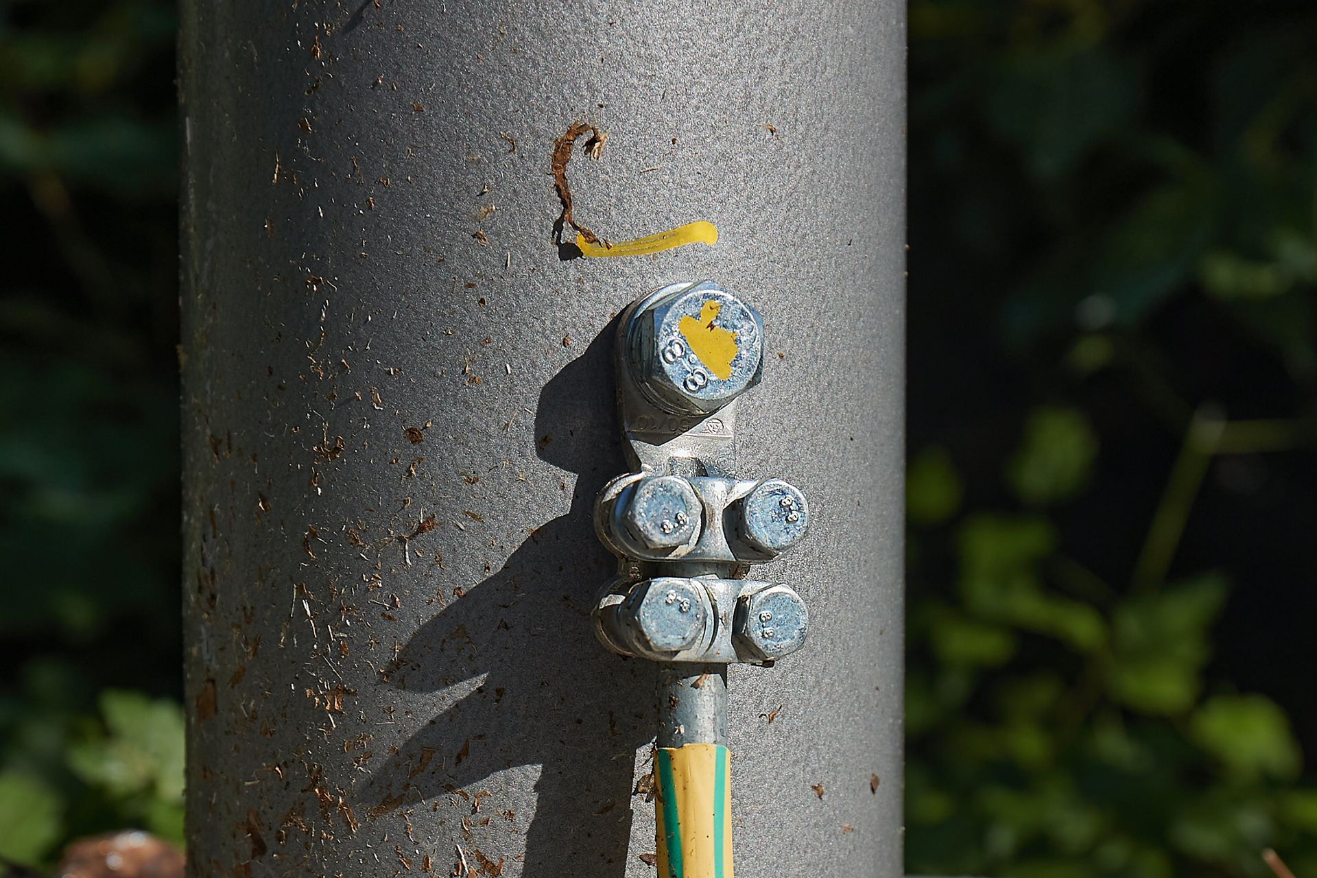 A close up of a metal pole with a yellow and green wire attached to it.