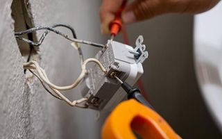 a mr sparky electrician using a screwdriver to fix a light switch .