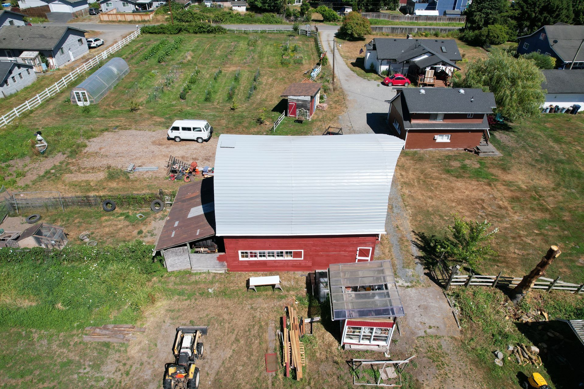 An aerial view of a red barn in the middle of a field taken by Riverside Roofing