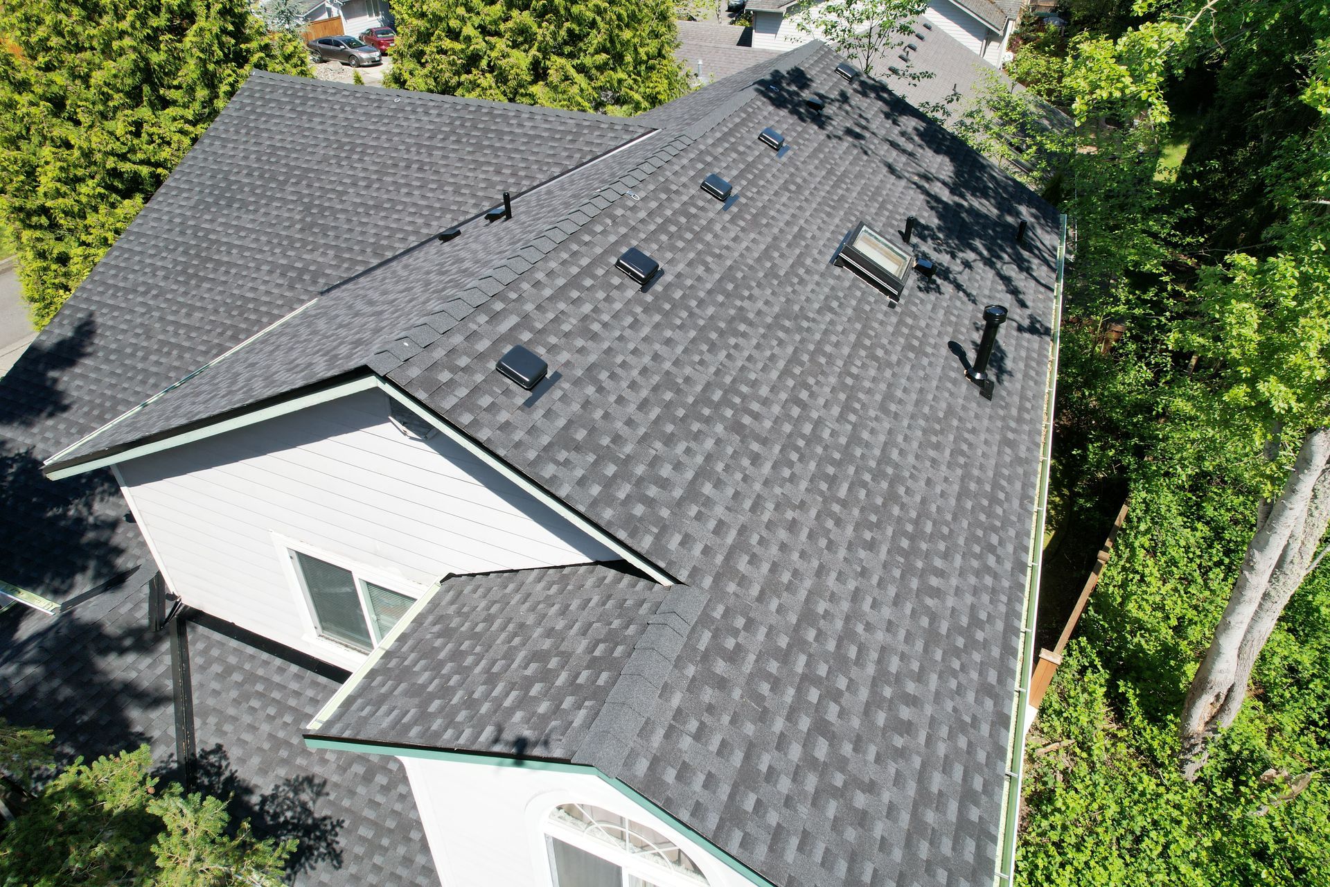 An aerial view of a house with a black roof taken by Riverside Roofing