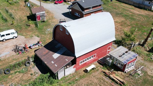 An aerial view of a red barn with a white roof