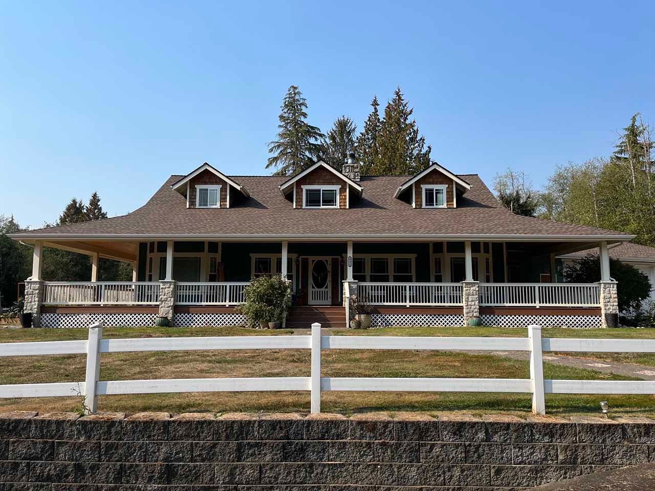 A large house with a white fence in front of it taken by Riverside Roofing