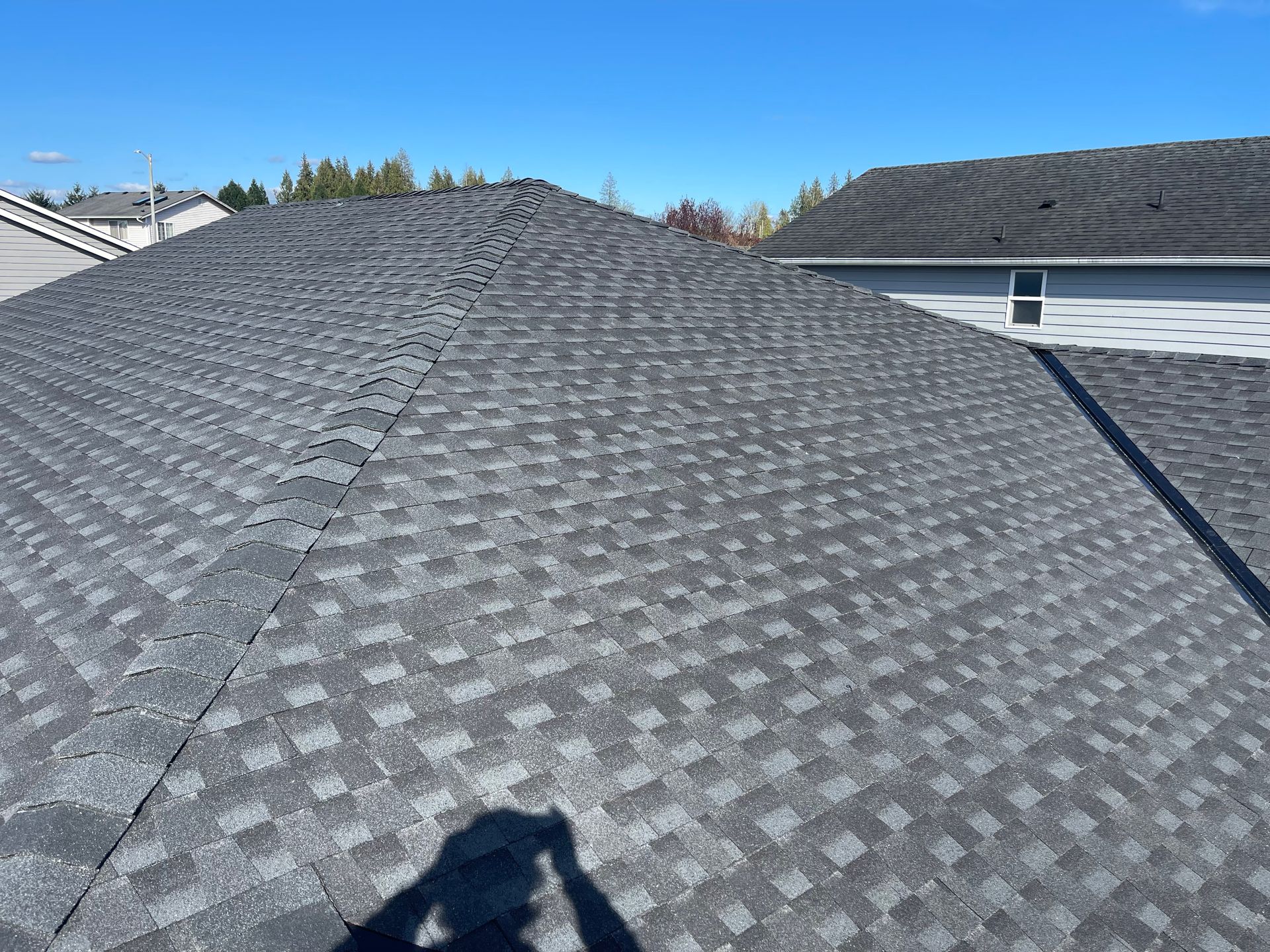 A person is taking a picture of the roof of a house taken by Riverside Roofing