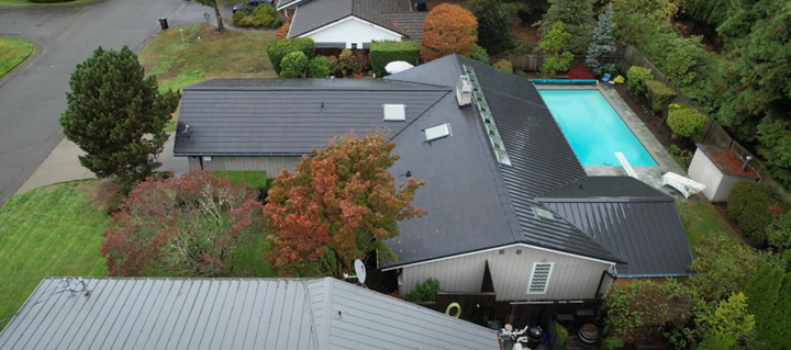 An aerial view of a house with a pool in the backyard with a new metal roof done by Riverside Roofing