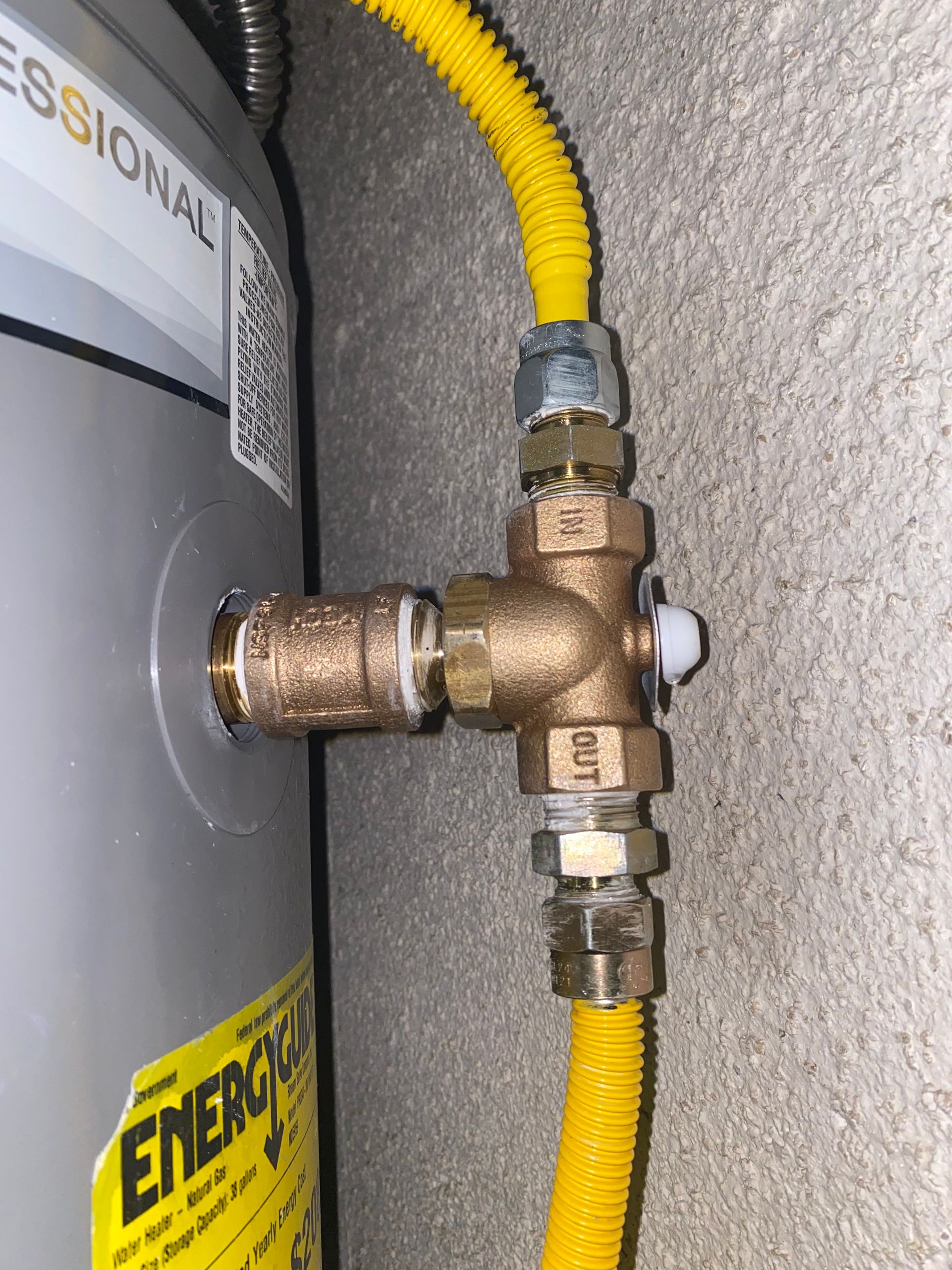 A close up of a water heater with a yellow hose attached to it.