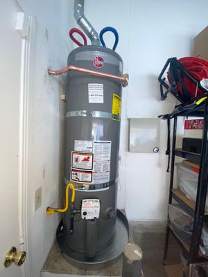 A gray water heater is sitting in a room next to a door