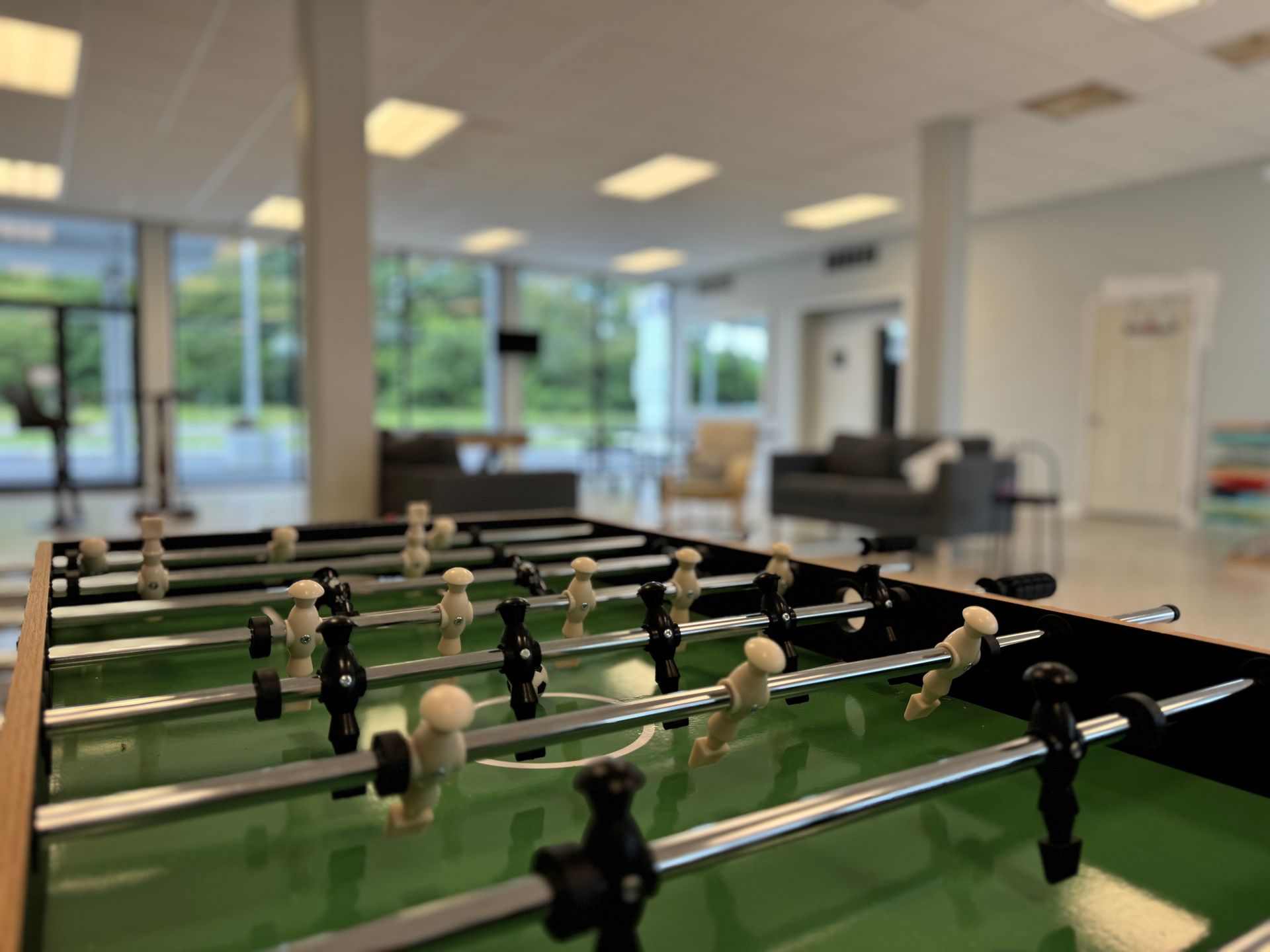 A foosball table is in a room with a lot of windows.