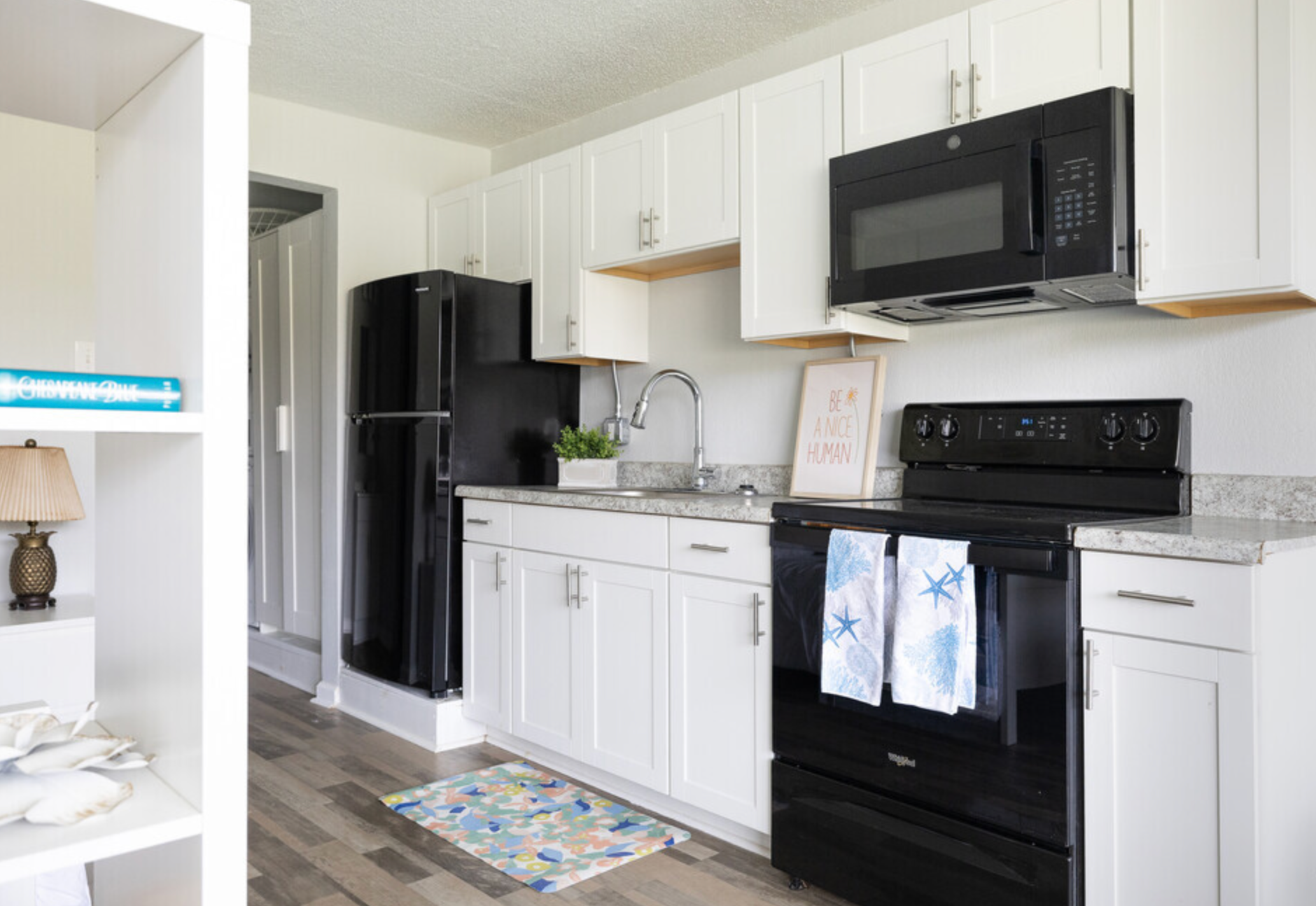 A kitchen with white cabinets , a black stove , a black refrigerator , and a black microwave.
