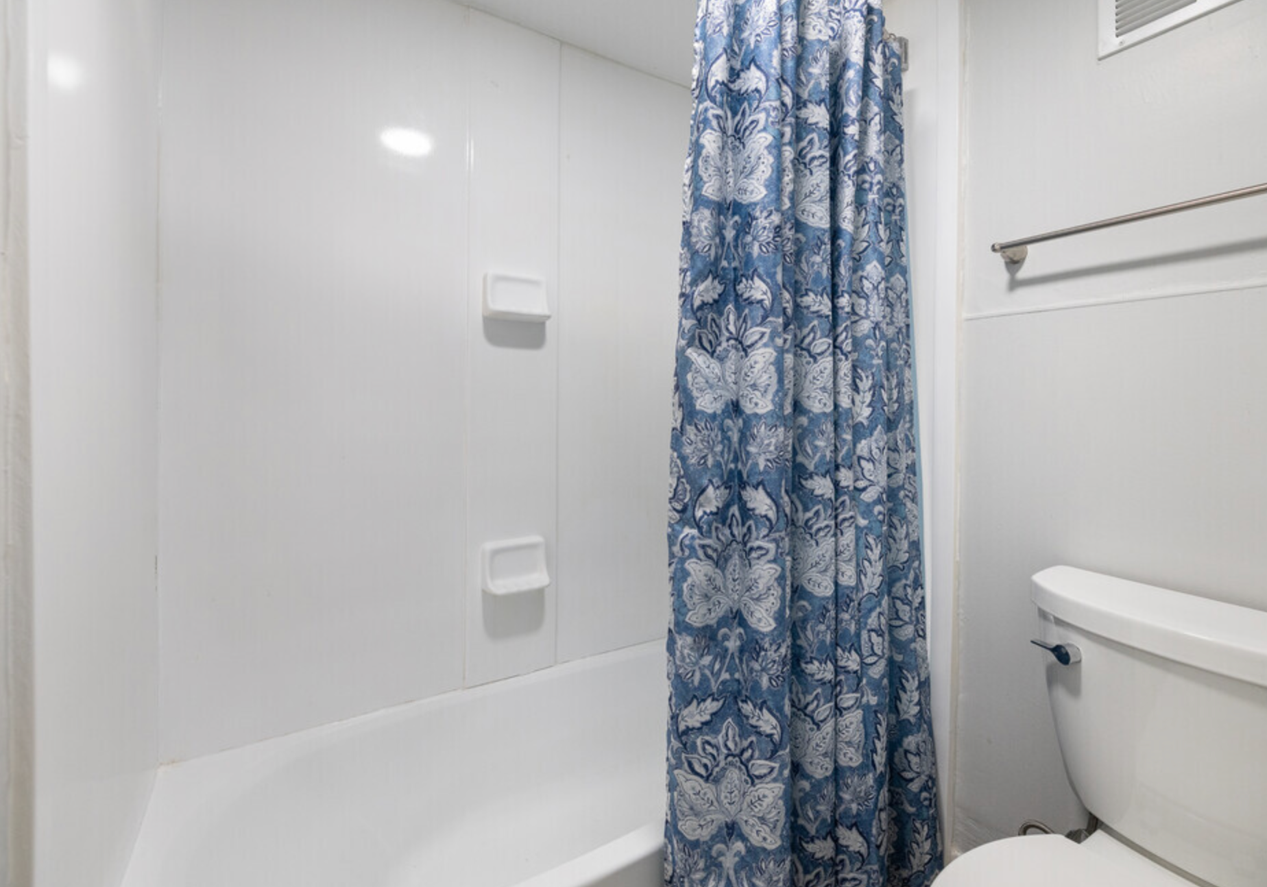 A bathroom with a bathtub , toilet and shower curtain.