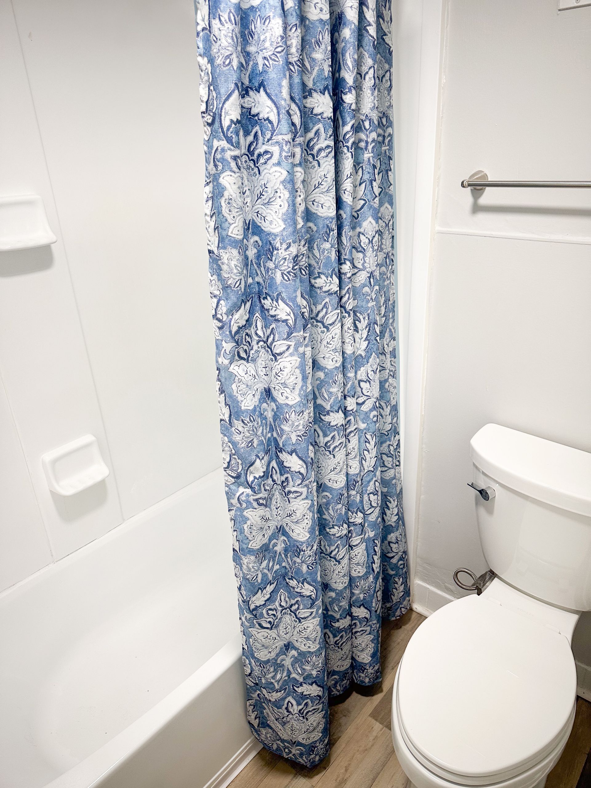 A bathroom with a toilet , bathtub and shower curtain.