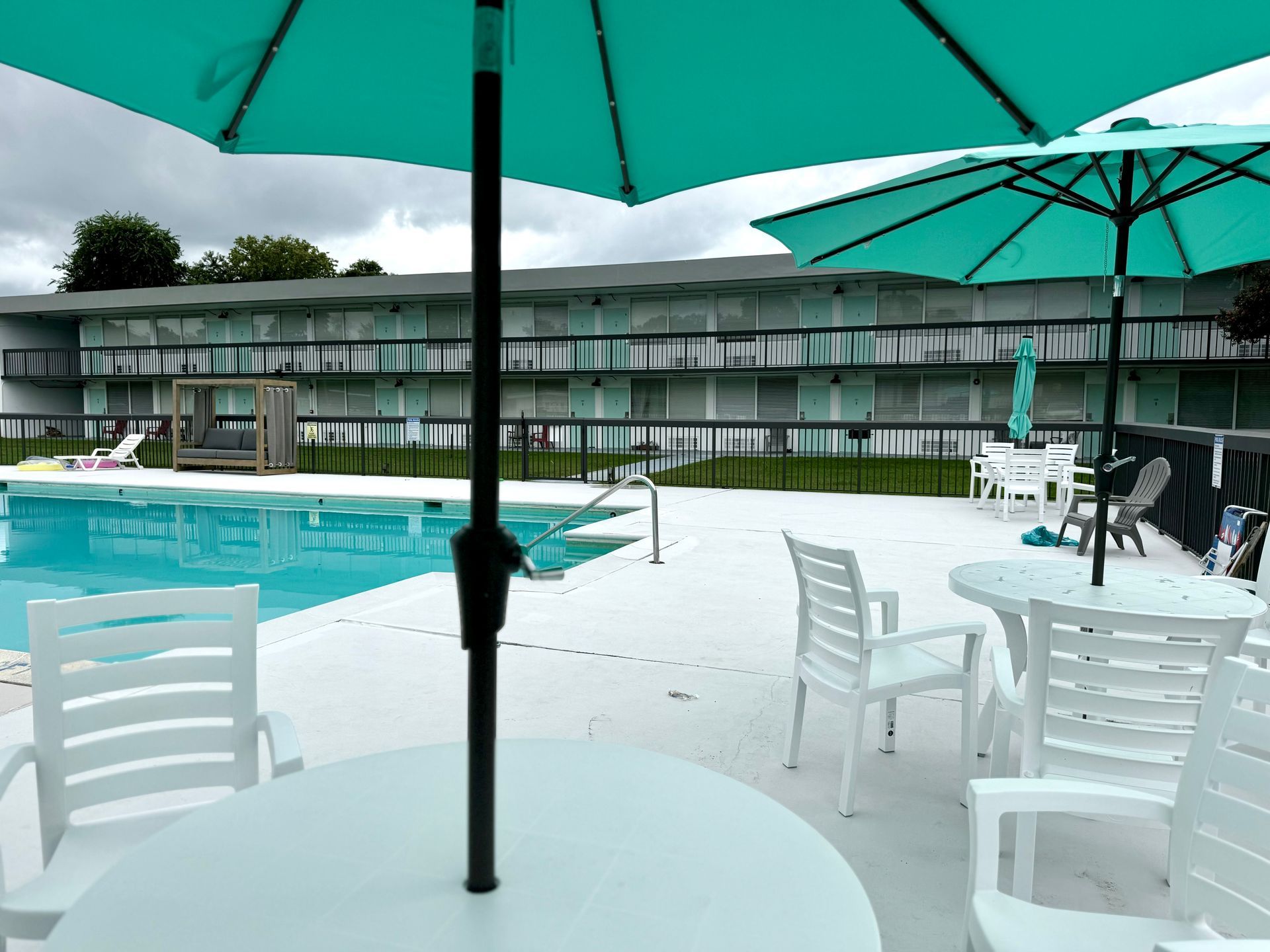 A swimming pool is surrounded by tables and chairs with umbrellas.