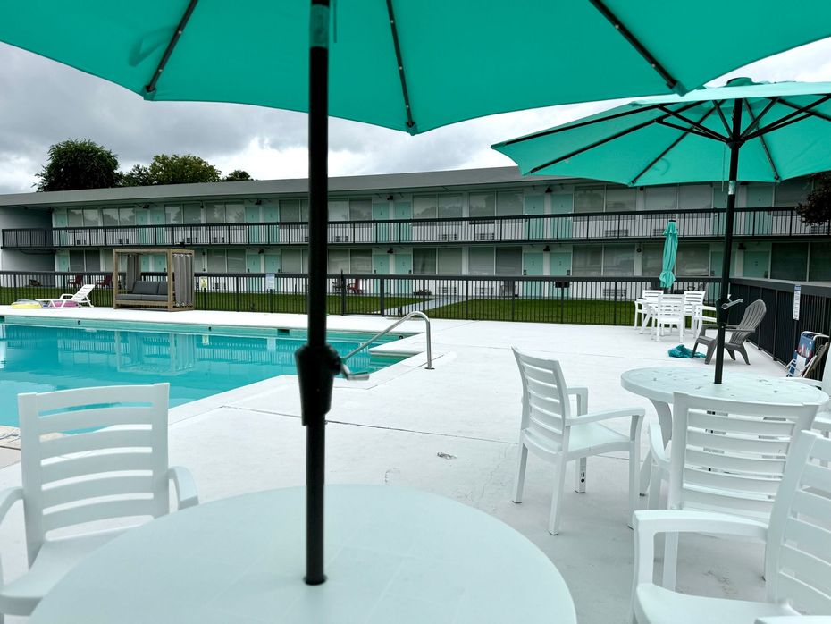 A swimming pool is surrounded by tables and chairs with umbrellas.