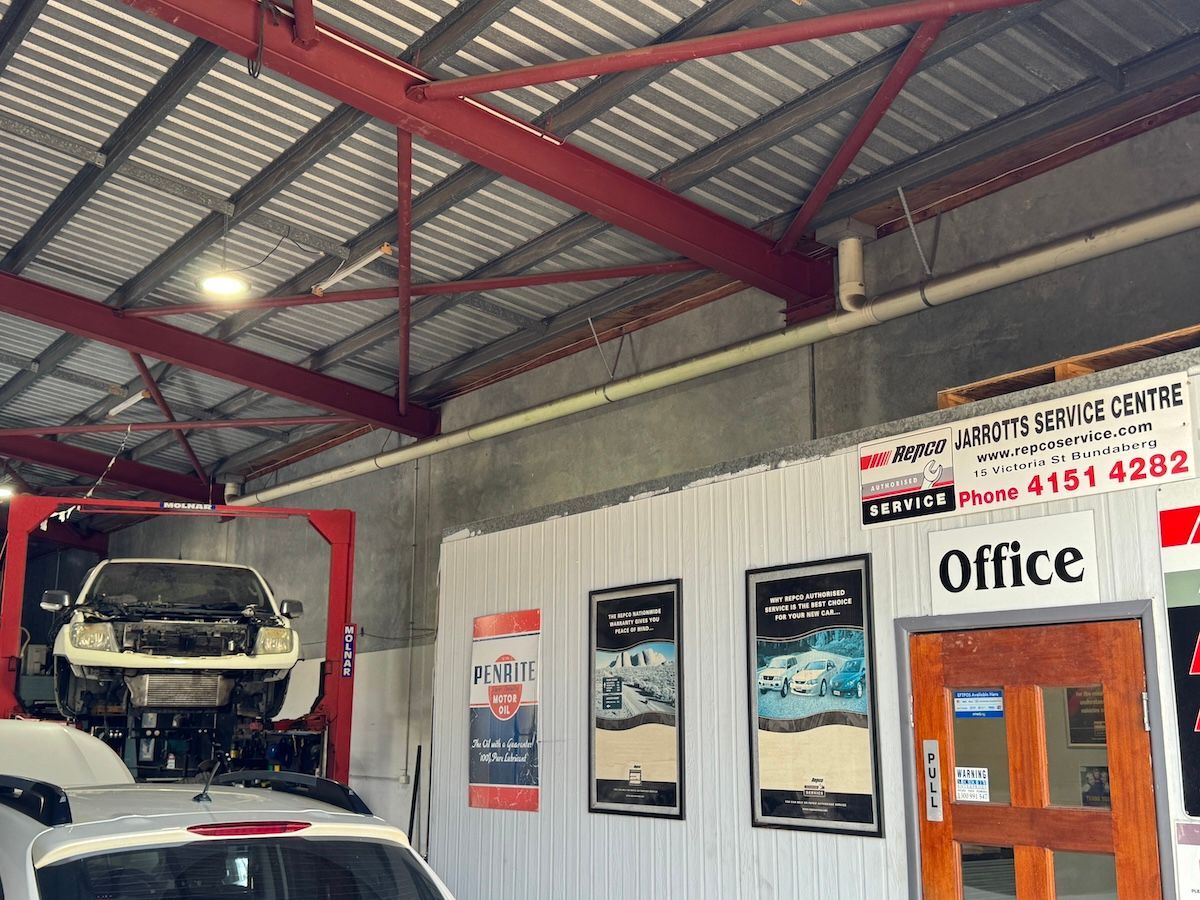 A White Car Is Driving Down A Road With Trees In The Background — All Automotive Services In Bundaberg East, QLD
