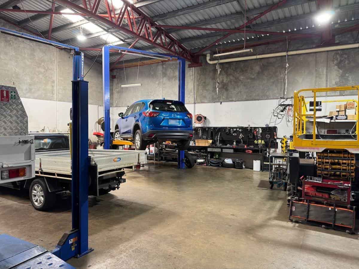 A Blue Car Is Sitting On A Lift In A Garage — All Automotive Services In Bundaberg East, QLD