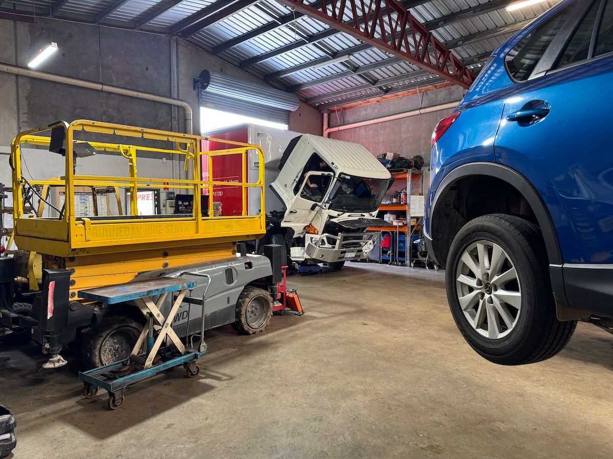 A blue car is parked in a garage next to a yellow scissor lift — All Automotive Services In Bundaberg East, QLD