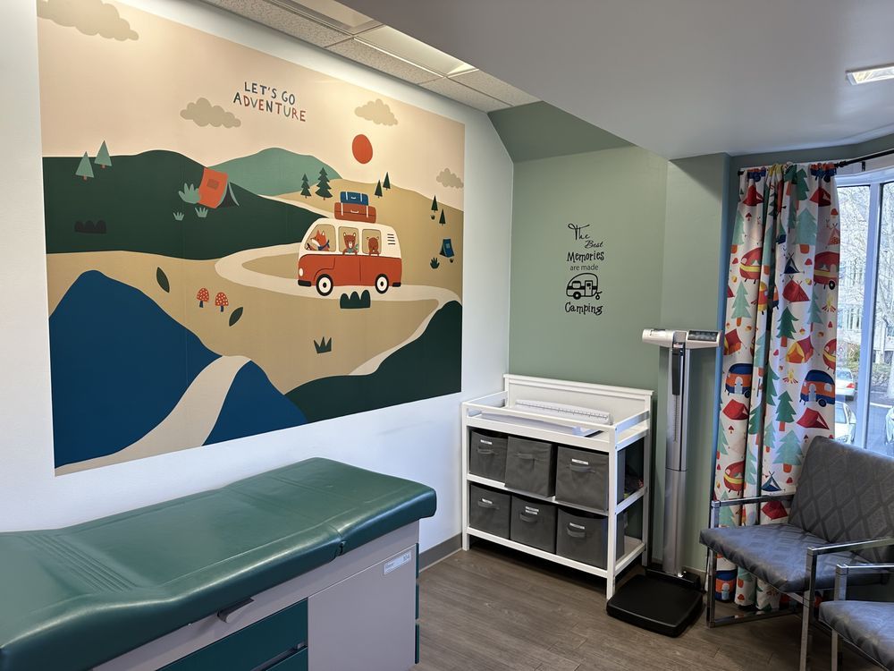 A doctor 's office with a painting on the wall and a changing table.