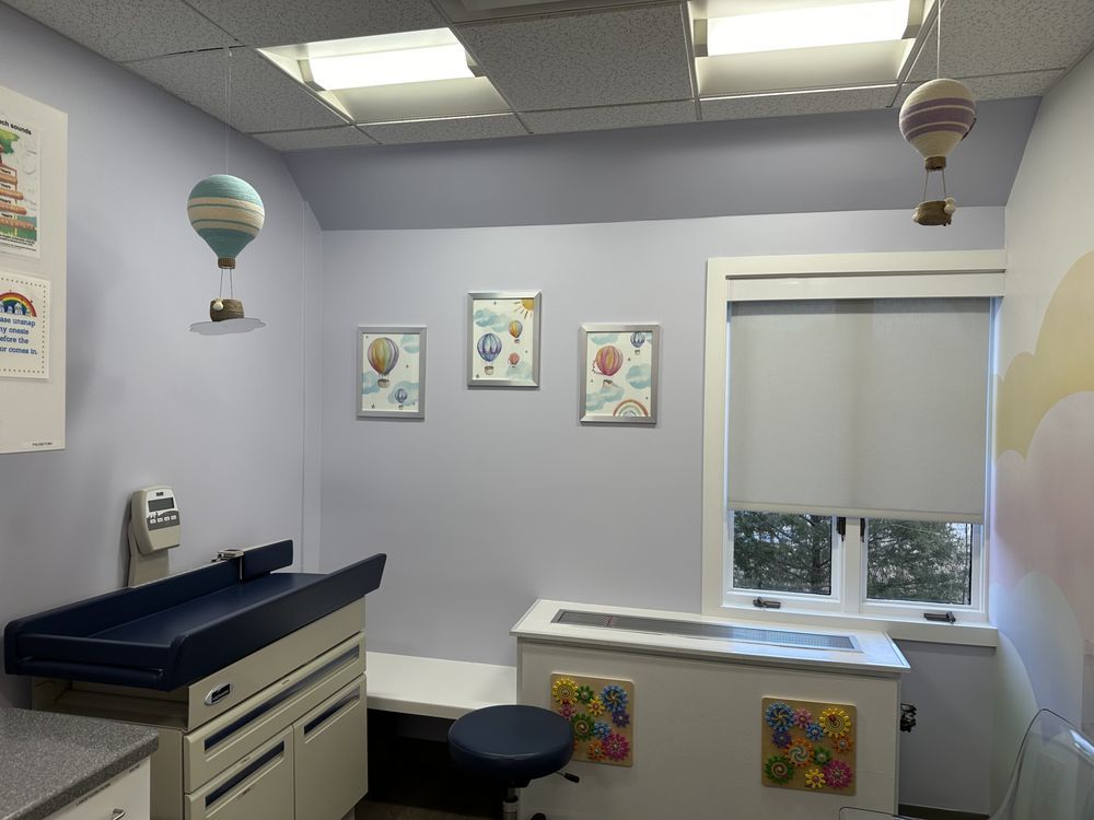 A doctor 's office with balloons hanging from the ceiling and a changing table.