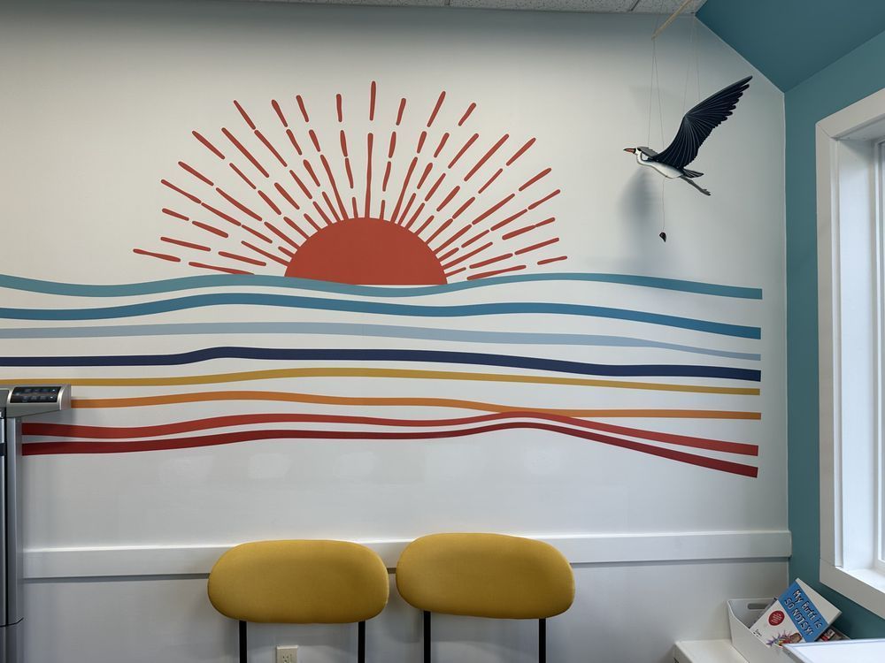 A wall with a painting of a sunset over the ocean
