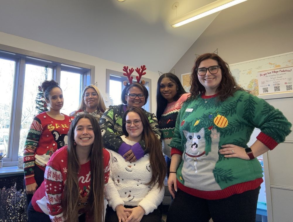 A group of women wearing christmas sweaters are posing for a picture.