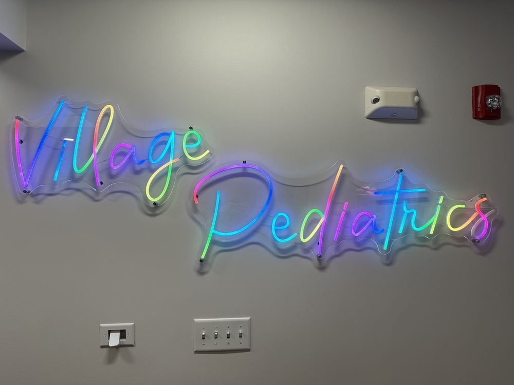 Colorful neon sign spelling out village pediatrics