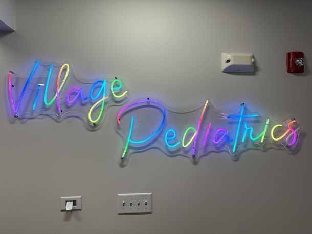 Colorful neon sign spelling out village pediatrics