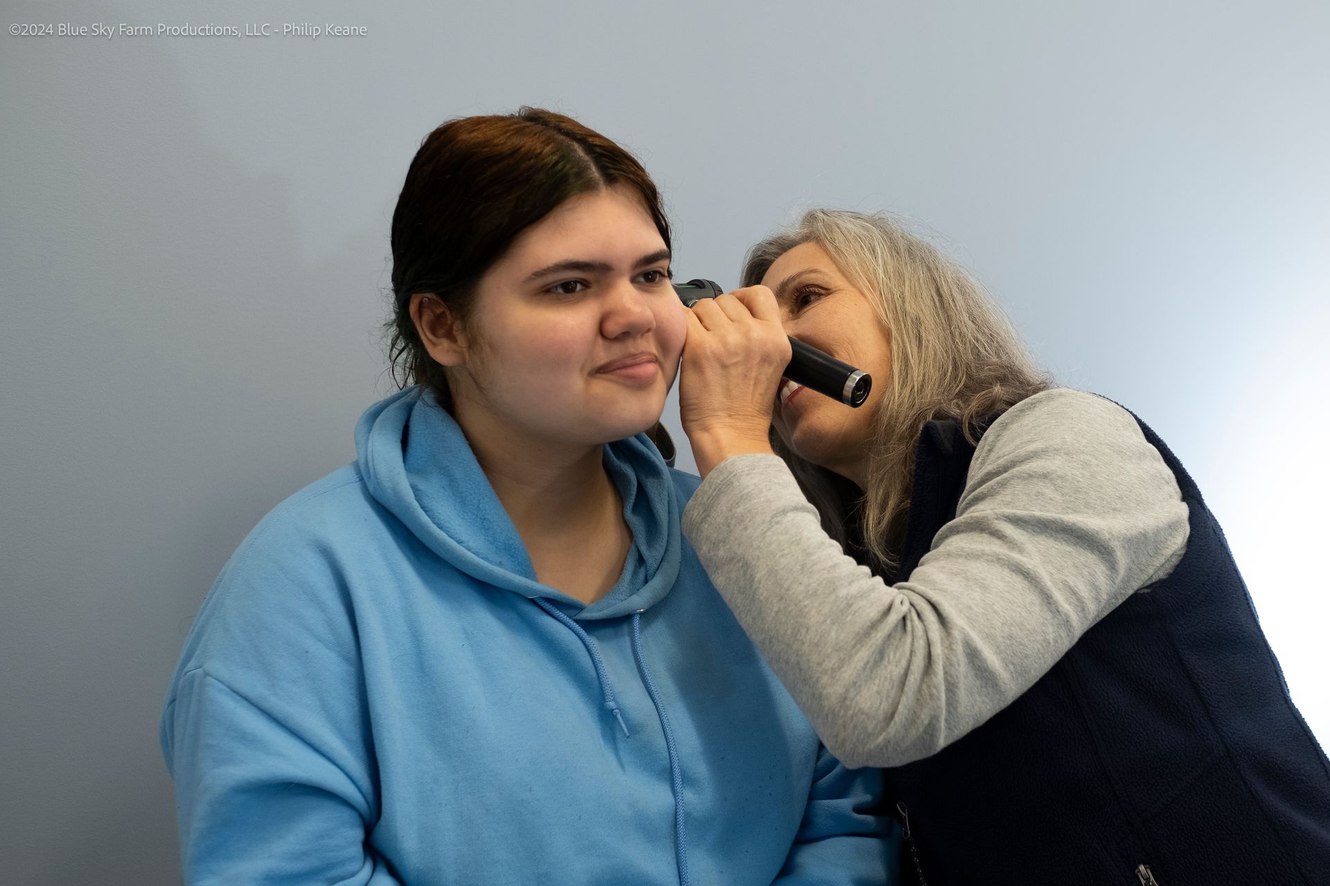 Pediatrician looking into the ear of a sick teen