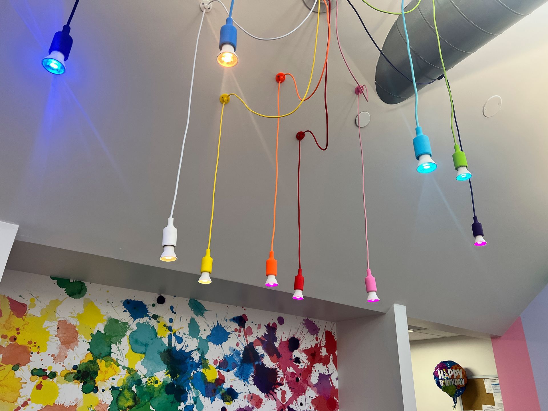 A bunch of colorful lights are hanging from the ceiling