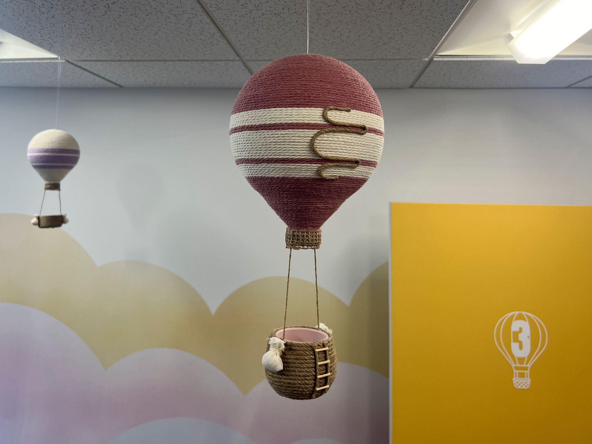 Three hot air balloons are hanging from the ceiling in a room