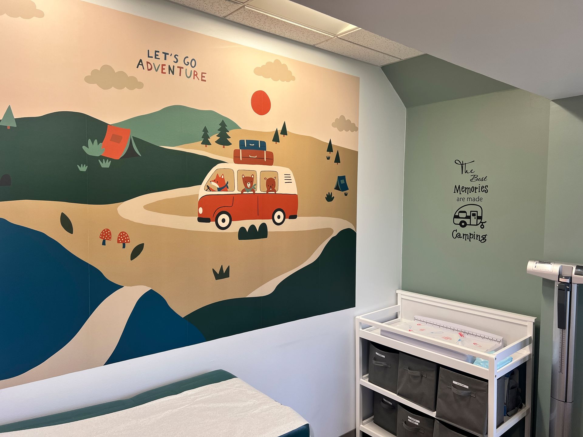 A room with a mural on the wall and a changing table.