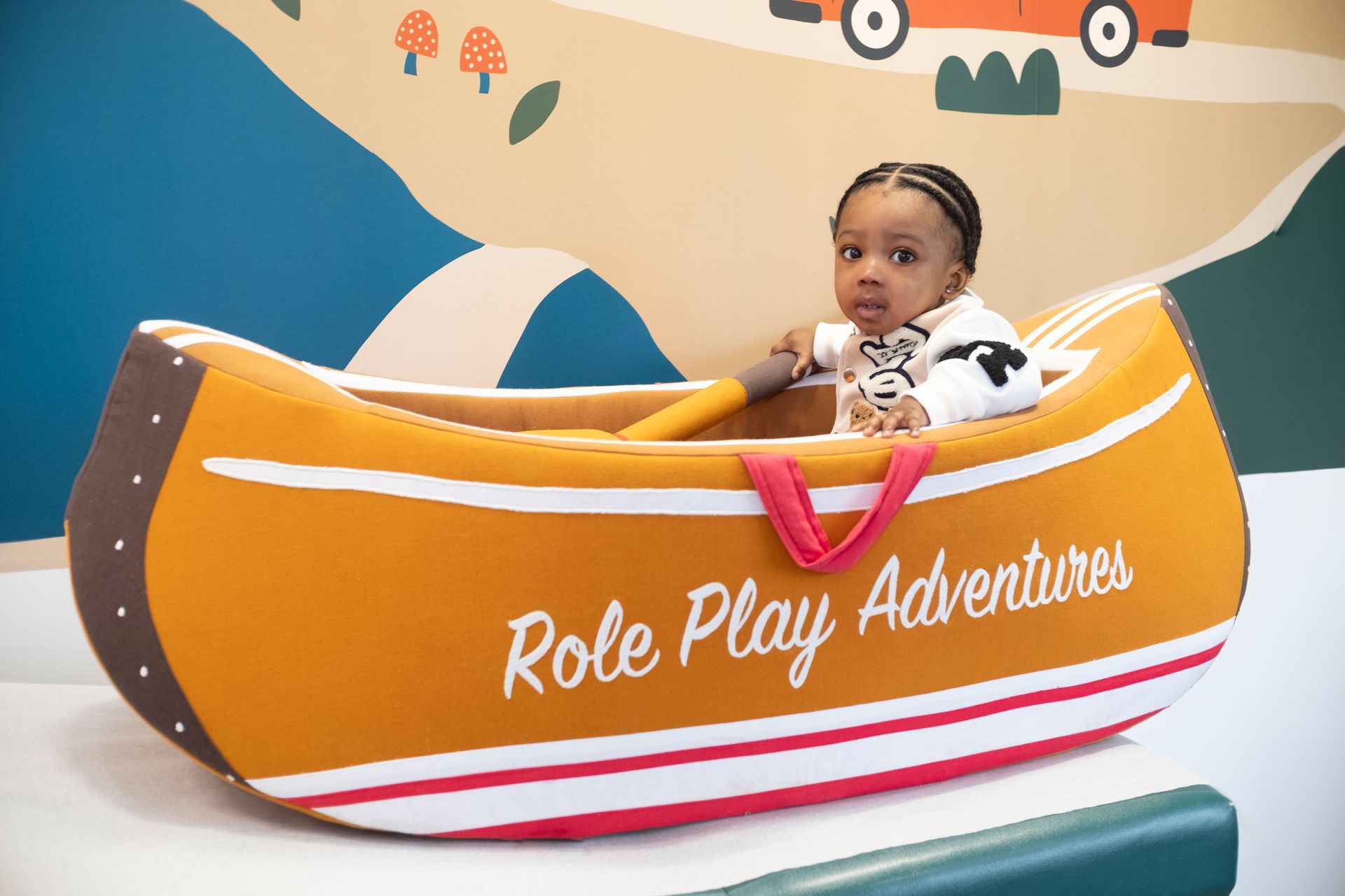 Small child in a toy canoe with wording on it, 