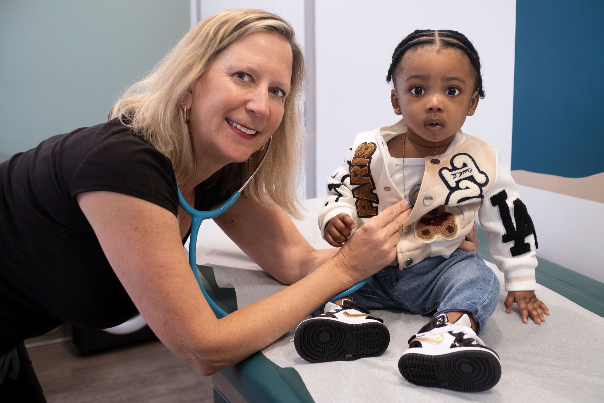 Smiling pediatrician with a baby on a medical table.